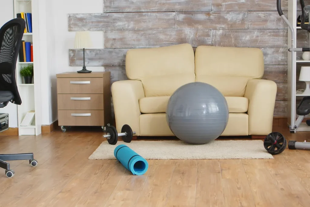 An empty room featuring an elliptical machine and a fitness ball, highlighting specialized physical therapy equipment.