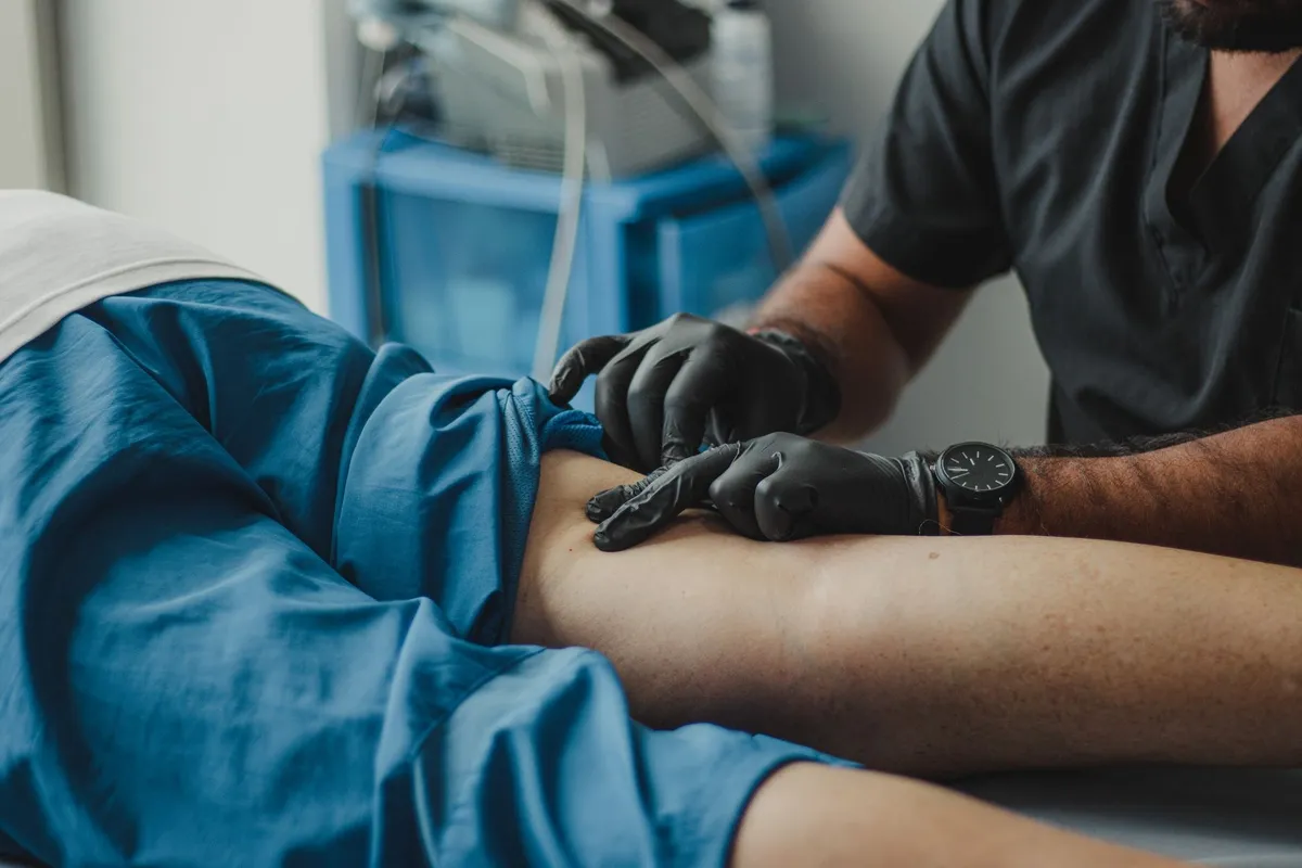 A healthcare professional in gloves treats a patient, illustrating a typical physical therapy session.