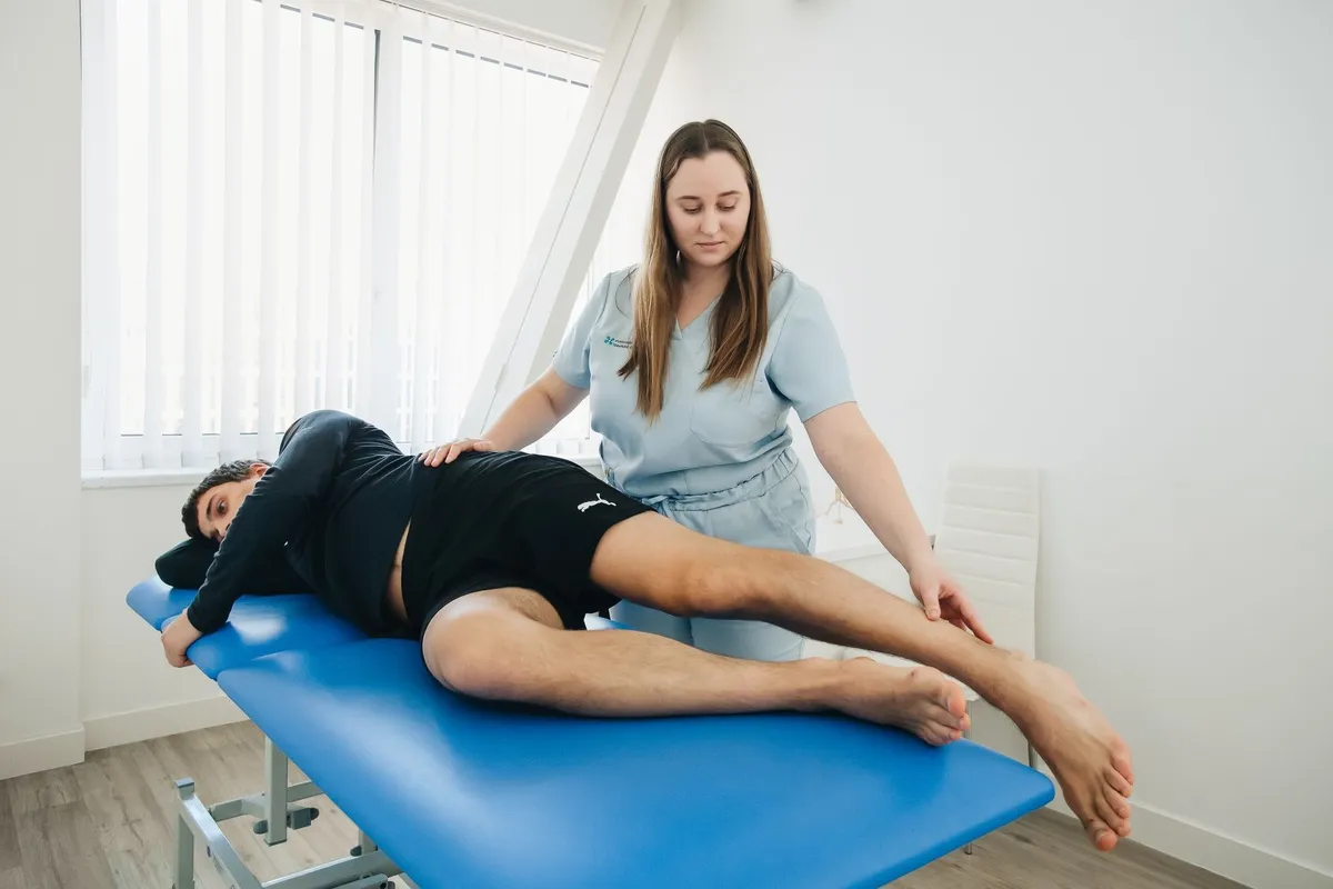 A physiotherapist helps a patient during a rehabilitation session, highlighting the importance of insurance for access.
